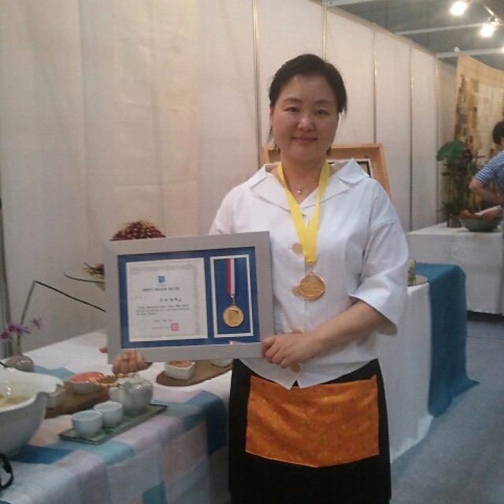 Jang Young-Hea holding an award certificate and medal